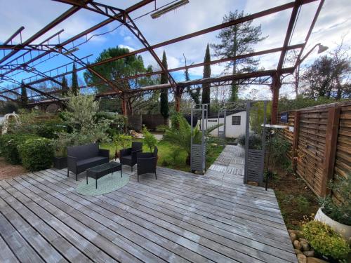 Un jardín con terraza de madera con sillas y pérgola. en La GARE de Lamalou, en Lamalou-les-Bains