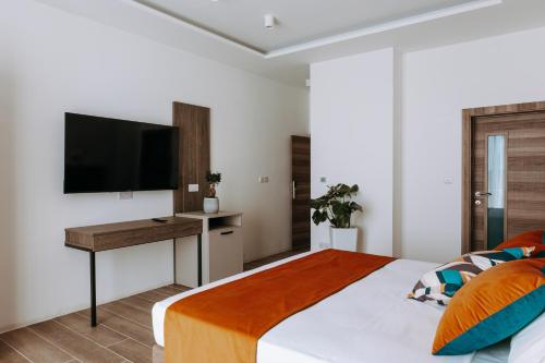 a bedroom with a bed with a desk and a television at Blu Waters Boutique Hotel in Xlendi