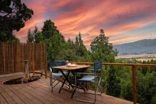 una mesa y sillas en una terraza con puesta de sol en Casa Terraplen con tina privada y vista a la laguna en Trevelín