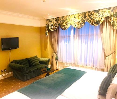 a bedroom with a bed and a chair and a television at The Colonnade in London