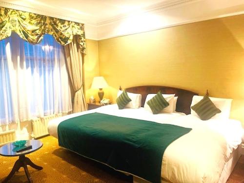 a bedroom with a large bed with a green blanket at The Colonnade in London
