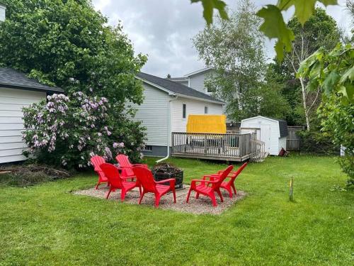 a group of red chairs sitting in a yard at Cozy chalet near the beach in Shediac