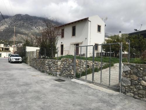 a white house with a fence and a stone wall at Papa-Antonis Stone House in Zarós