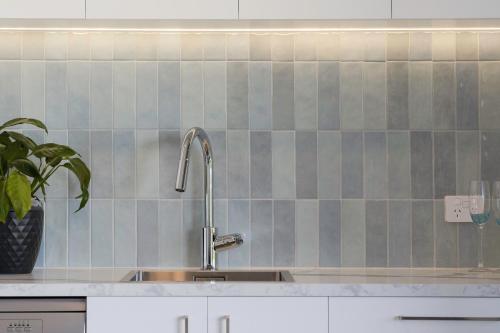 Una cocina con fregadero y pared de azulejos. en Pukehina Estuary Sunset Views Studio, en Pukehina