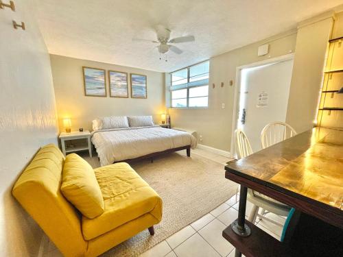 a living room with a yellow couch and a bed at Sunset Studio Daytona Beachfront in Daytona Beach
