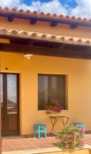 a yellow house with a table and a window at Hotel Su Nuraxi in Barùmini