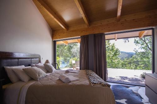 ein Schlafzimmer mit einem großen Bett und einem großen Fenster in der Unterkunft Quinta dos Carqueijais Gerês in Geres