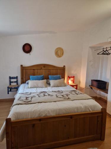 a bedroom with a large wooden bed with blue pillows at Monte das Cobras - Country House in Évora