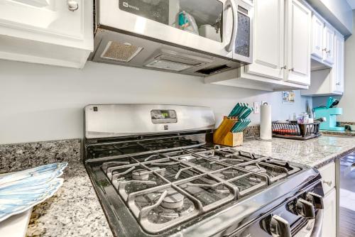 a stove top oven in a kitchen with white cabinets at Seaside Heights Condo with Deck Walk to Boardwalk! in Seaside Heights