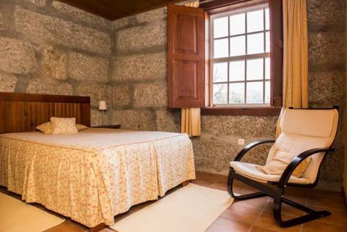 een slaapkamer met een bed, een stoel en een raam bij Casa de Andrães Magnolias in Marco de Canavezes