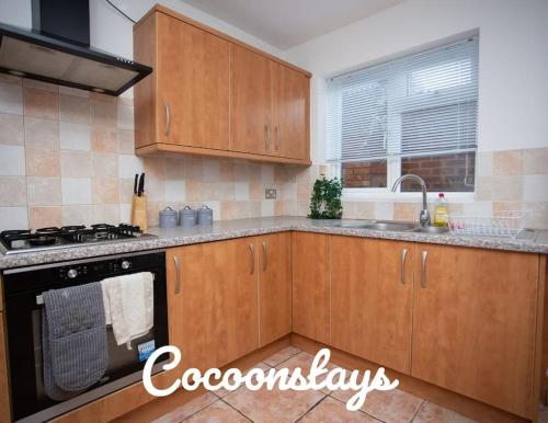 a kitchen with wooden cabinets and a stove top oven at Cocoonstays Short Lets and Serviced Accommodation Luton in Luton