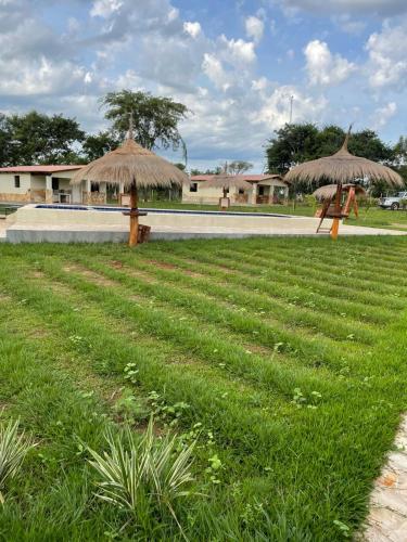 two straw umbrellas sitting in a field of grass at Residencia Piri 1 in Piribebuy