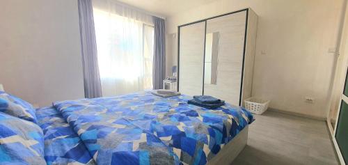 una camera da letto con un letto con un piumone blu e uno specchio di Апартамент Синчец a Sofia