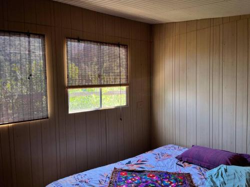 um quarto com uma cama e duas janelas em Cabaña ecológica y aislada em Santiago