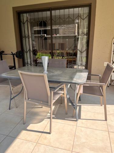 a dining room table with chairs and a table and a window at 3 Bedroom in Secure Estate Loadshedding free in Midrand