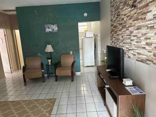 a living room with a tv and two chairs at Casa de praia p/ família, confortável, bem arejada in Serra