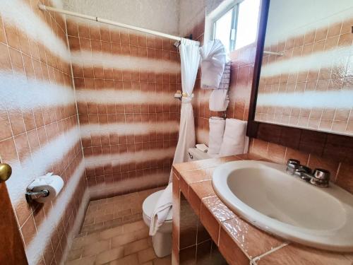 La salle de bains est pourvue d'un lavabo, de toilettes et d'un miroir. dans l'établissement Buena Vista Oceanfront & Hot Springs Resort, à Buenavista