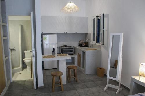 a kitchen with white cabinets and a counter with stools at Fabio Studios in Kionia