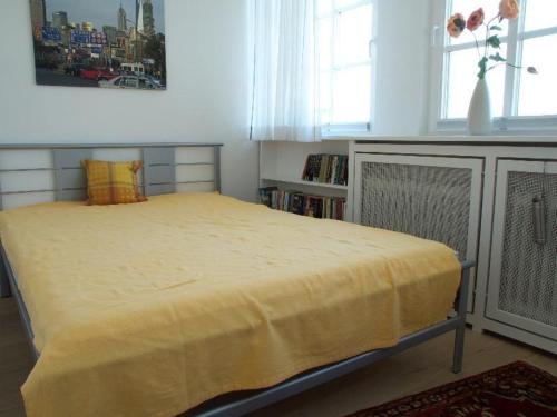 a bedroom with a large bed with a yellow blanket at Haus-Archsum in Archsum