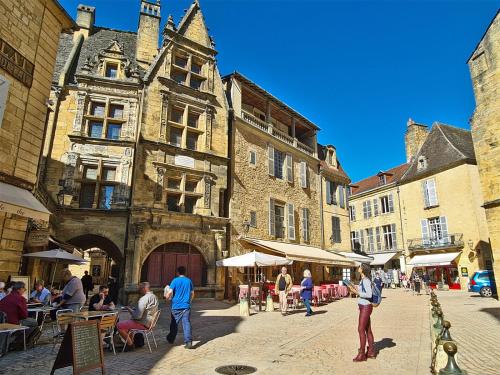 a group of people walking around a street with buildings at Pause Dordogne Ambiance Cozy à Sarlat in Sarlat-la-Canéda