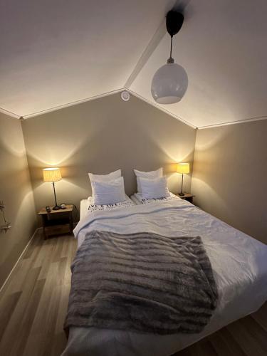a bedroom with a large white bed with two lamps at Stuga med havsutsikt in Robertsfors