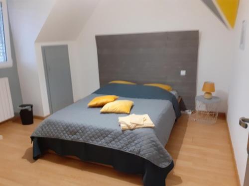 - une chambre avec un grand lit bleu et des oreillers jaunes dans l'établissement Bretagne, à Quéven