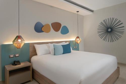 a bedroom with a large white bed and two lights at Wyndham Alltra Samana All Inclusive Resort in Las Galeras
