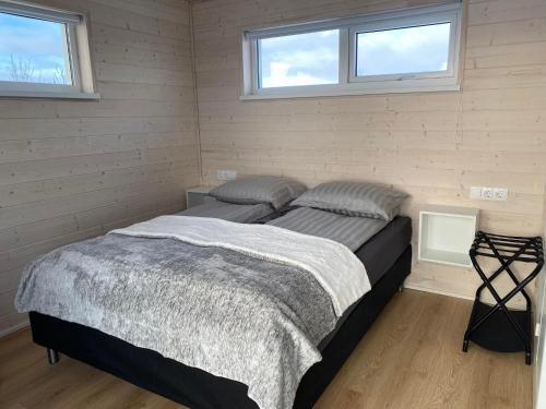 een slaapkamer met een bed in een kamer met 2 ramen bij Ugla Gistihús (Ugla Guesthouse) in Hella
