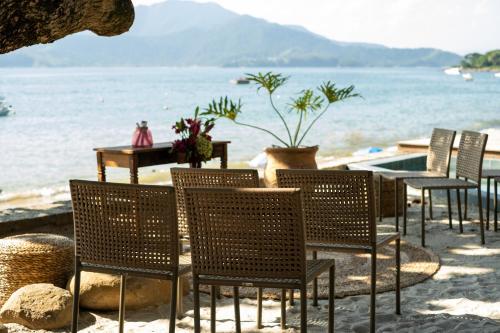 a row of chairs on a beach with the water at Wyndham Ilhabela Casa Di Sirena in Ilhabela