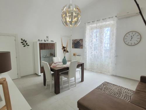 une salle à manger avec une table, des chaises et une horloge dans l'établissement JEY STUDIO_INDEPENDENT SEAFRONT APARTMENT, à Terrasini