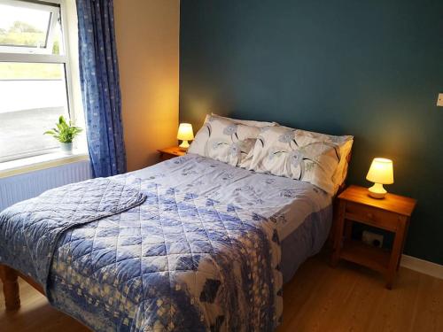 a bedroom with a bed and two lamps on tables at Woodmount Cottage in Ennistymon