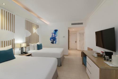 a hotel room with two beds and a flat screen tv at Wyndham Alltra Samana All Inclusive Resort in Las Galeras