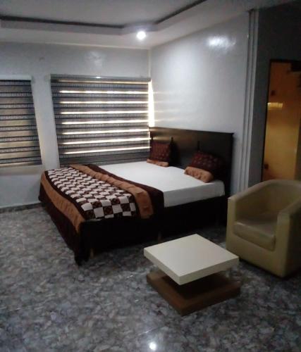 a bedroom with a large bed and a chair at Kemi hotel in Ikeja