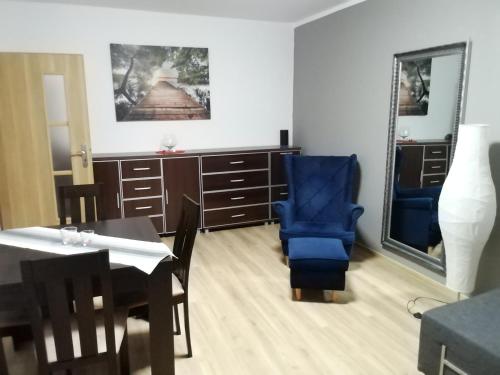 a dining room with a blue chair and a table at Apartament Szept Plaży in Kołobrzeg