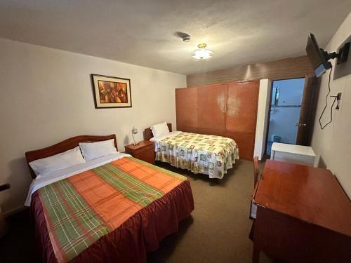 a hotel room with two beds and a window at Hotel el sol de los incas in Los Baños del Inca