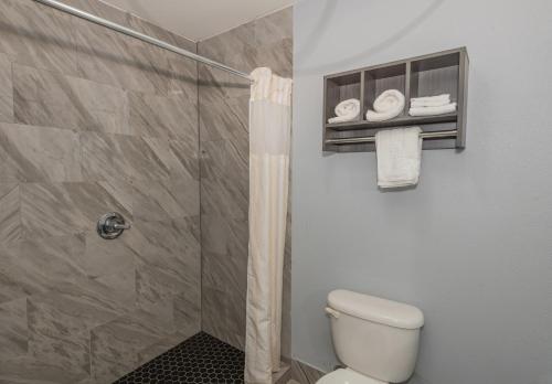 a bathroom with a shower and a toilet and towels at Jamestown inn & Suites in Riverdale