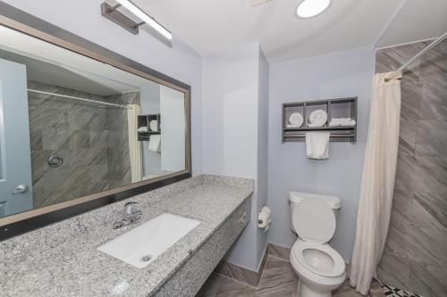 a bathroom with a toilet and a sink and a mirror at Jamestown inn & Suites in Riverdale