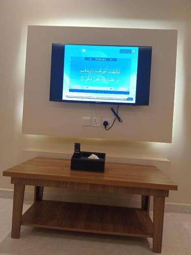 a television on a wall with a wooden table at فندق دره الراشد للشقق المخدومه in Riyadh