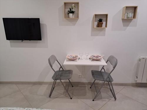 a white table with two chairs and a tv on a wall at Studio Beauvais in Beauvais