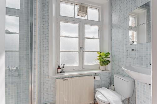 a bathroom with a toilet and a sink and a window at Cosy & Stylish London Apartment in London