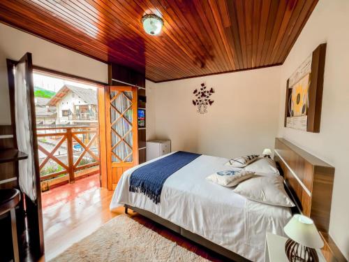 a bedroom with a bed and a wooden ceiling at Pousada Avenida in Monte Verde