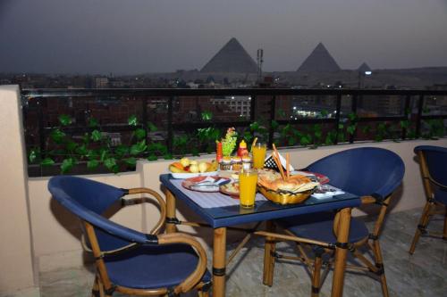 - une table avec de la nourriture et des boissons sur le balcon dans l'établissement Sneferu Pyramids inn - Full Pyramids View, au Caire