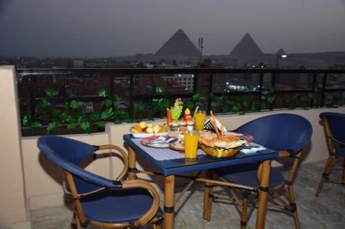 una mesa con comida y bebida en la parte superior de un balcón en Sneferu Pyramids inn - Full Pyramids View en El Cairo
