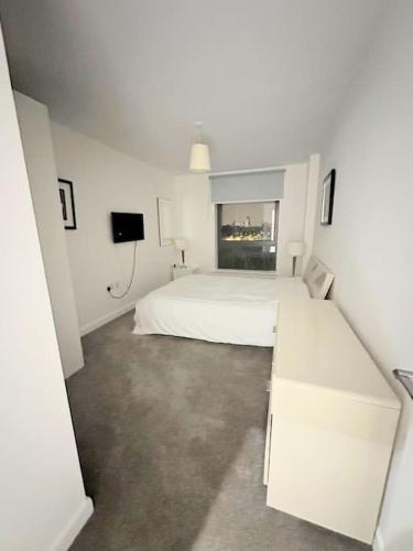 - une chambre blanche avec un lit et une télévision dans l'établissement 3 bed apartment near CanaryWharf, à Londres