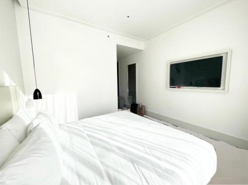 a bedroom with a white bed with a tv on the wall at Most City Area Lux Studio in Dnipro