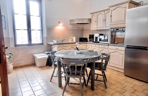 y cocina con mesa, sillas y nevera. en 100 m2 de charme vue sur la Loire, en Saint-Clément-des-Levées