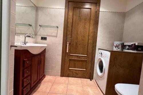 a bathroom with a washing machine and a wooden door at Fantástico apartamento con vistas a Llivia in Llivia
