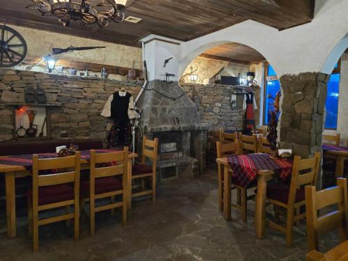 um restaurante com mesas e cadeiras e uma parede de pedra em Комитите em Troyan