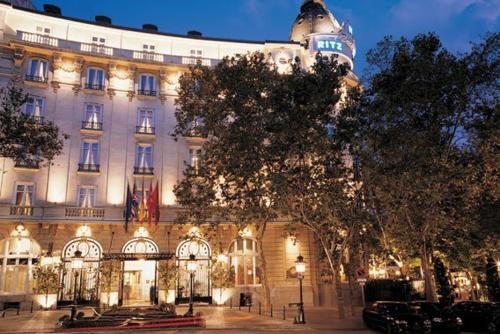 un edificio iluminado con un árbol delante de él en La Casita del Retiro en Madrid