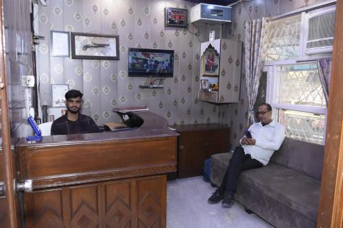 two men sitting at a counter in a room at Hotel Royal Inn in New Delhi